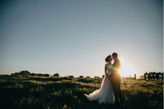 A bride and groom in a field in Tuscany at sunset.