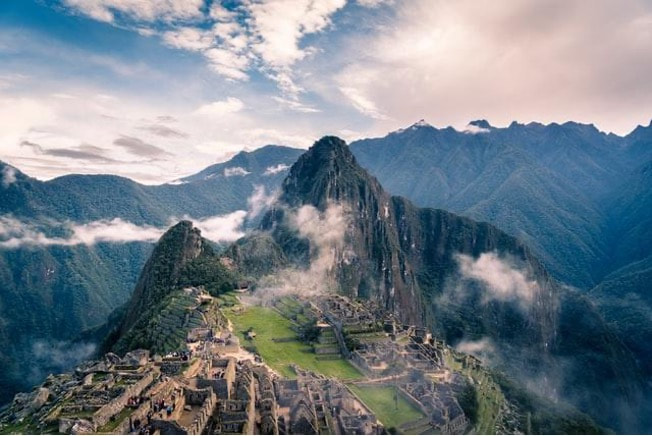 A view at Machu Picchu with clouds surrounding it.